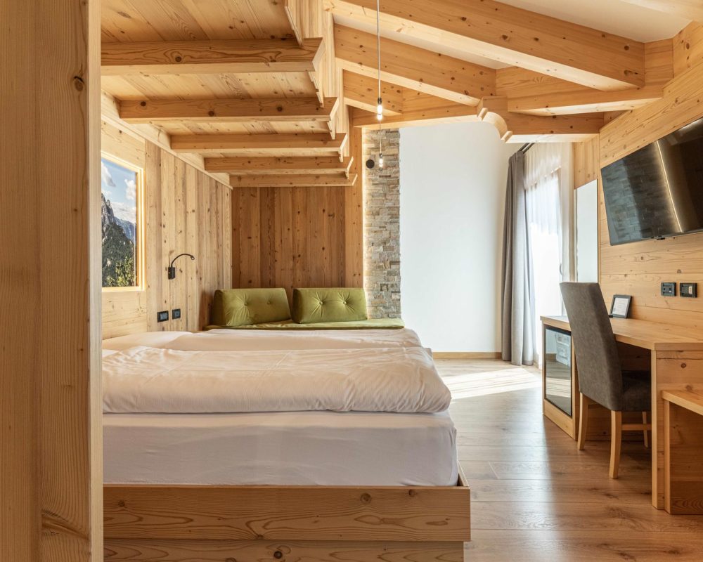 ista ravvicinata del letto matrimoniale nello Chalet Alaska, con murale di montagne retroilluminato sopra la testiera in legno e scrivania adiacente con sedia.