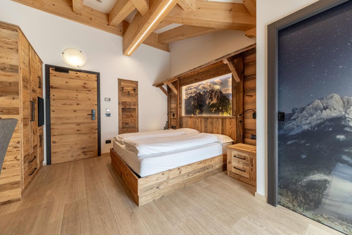 Letto matrimoniale e armadio in legno massiccio in una stanza da letto di uno chalet moderno.